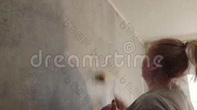 一个女人用滚筒在粉刷<strong>墙壁</strong>之前对<strong>墙壁</strong>进行处理。